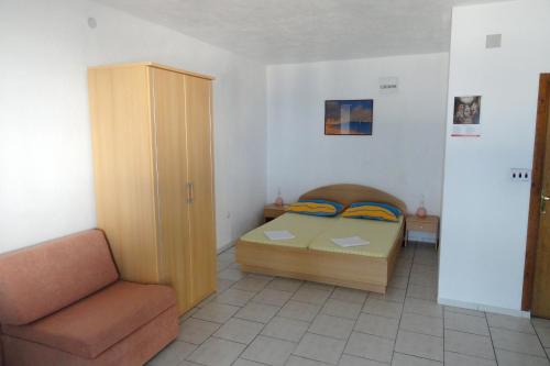 um pequeno quarto com uma cama e uma cadeira em Seaside apartments with a swimming pool Businci, Ciovo - 11232 em Trogir