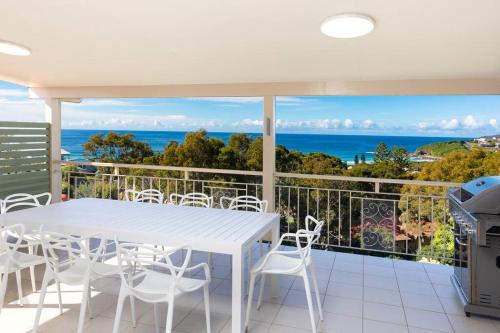 a white table and chairs on a balcony with the ocean at Becker Bliss - Ocean views, 5 bedrooms, sleeps 14 in Forster