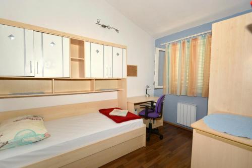 niewielka sypialnia z łóżkiem i biurkiem w obiekcie Apartments by the sea Suhi Potok, Omis - 11401 w mieście Jesenice
