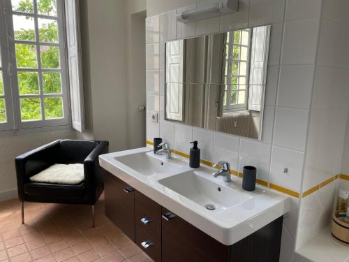 ein Badezimmer mit einem Waschbecken, einem Stuhl und einem Spiegel in der Unterkunft Hôtel Particulier, Maison Jazey. in Semur-en-Auxois