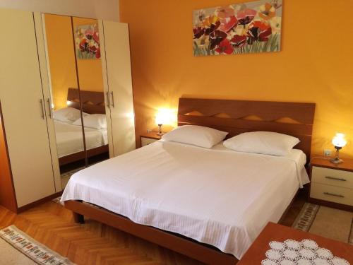 Schlafzimmer mit einem weißen Bett und einem Spiegel in der Unterkunft Apartments by the sea Arbanija, Ciovo - 11321 in Trogir
