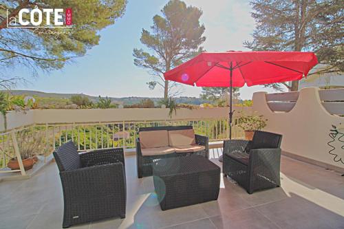 eine Terrasse mit einem Tisch, Stühlen und einem roten Regenschirm in der Unterkunft La Sourcinette T3 sur la côte Bleue Lacote Immo 1 in Carry-le-Rouet