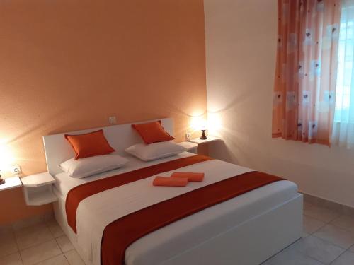 ein Schlafzimmer mit einem großen Bett mit zwei orangenen Kissen in der Unterkunft Apartments with a parking space Gradac, Makarska - 11332 in Gradac