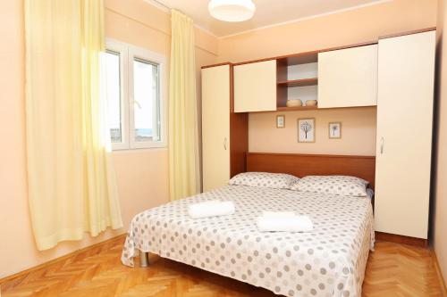 1 dormitorio con cama y ventana en Apartments by the sea Kastel Kambelovac, Kastela - 8679, en Kaštela