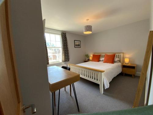 a bedroom with a bed with orange pillows and a table at Charming Cottage mins from Chichester City Centre in Chichester