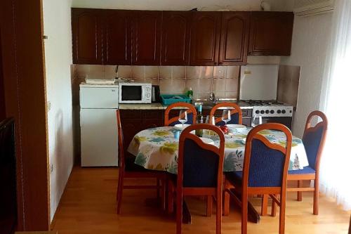 a kitchen with a table and four chairs and a refrigerator at Apartments for families with children Lopar, Rab - 10402 in Lopar