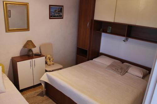 Dormitorio pequeño con cama y espejo en Apartments by the sea Pisak, Omis - 10410, en Mimice