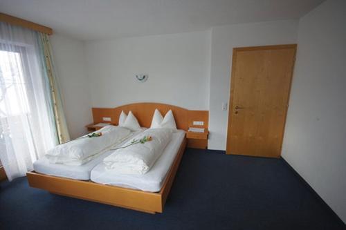 ein Schlafzimmer mit einem Bett mit weißer Bettwäsche und einer Tür in der Unterkunft Haus Hanser in Zellberg