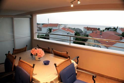 a table with chairs and a vase of flowers on a balcony at Apartments with a parking space Novalja, Pag - 6432 in Novalja