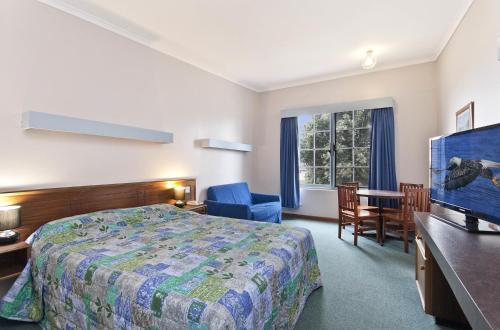 a hotel room with a bed and a desk and a television at William Dutton Motel in Portland