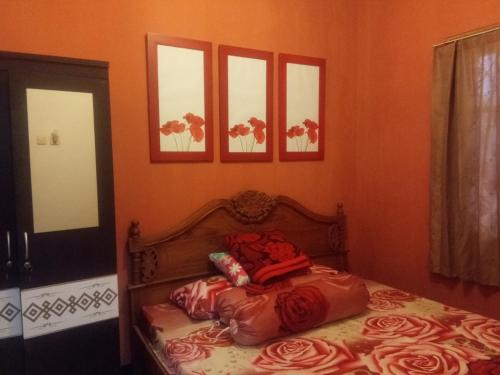 - un lit dans une chambre avec 4 photos sur le mur dans l'établissement Argolawu Homestay, à Tawangmangu