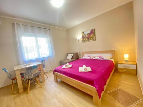 een slaapkamer met een bed met roze lakens en een bureau bij APARTMENTS NIK KOTOR in Kotor