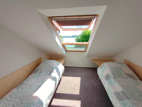 two beds in a small room with a window at Kasztanowe Wrota in Kosewo