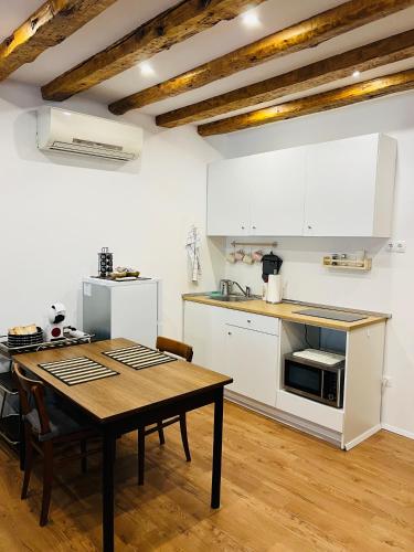una cucina con tavolo e una cucina con armadietti bianchi di Apartma Nicole a Piran