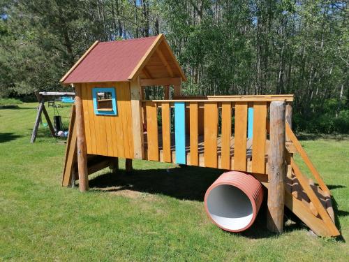 a wooden play house with a barrel in the grass at Kasztanowe Wrota in Kosewo