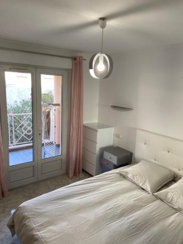 a bedroom with a bed and a sliding glass door at Appartement T4 très bien situé et climatisé in LʼÎle-Rousse