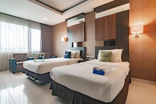 a hotel room with two beds and a chair at Urbanview Hotel Newton Riau Bandung by RedDoorz in Bandung