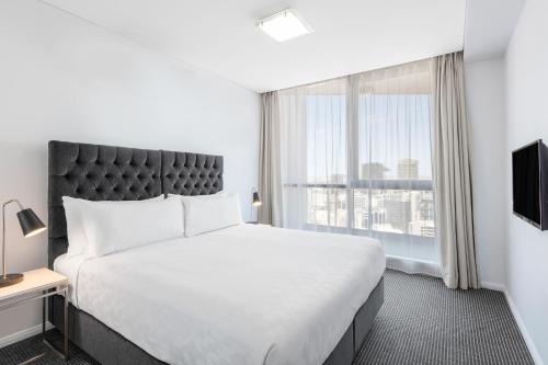 a bedroom with a large bed and a large window at Meriton Suites Campbell Street, Sydney in Sydney