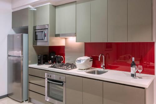 a kitchen with a sink, stove, and refrigerator at Meriton Suites Campbell Street, Sydney in Sydney