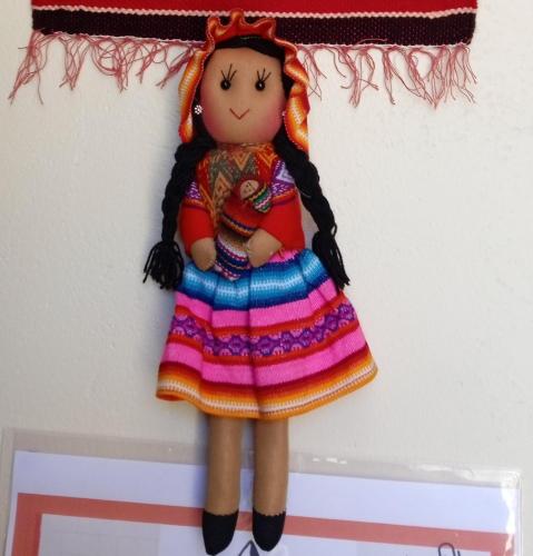 a doll of a girl in a colorful dress hanging on a wall at Ecolodge Casa del Montañista in Huaraz