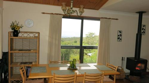 a dining room with a table and a large window at Ravensbourne Escape - Cedar Lodge in Ravensbourne
