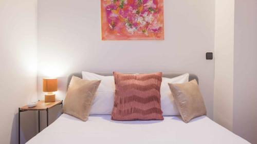 a bedroom with a bed with pillows and a painting at The Magic Place Dúplex junto a la Catedral by Toledo AP in Toledo