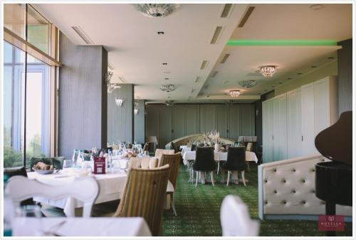 a dining room with white tables and chairs and windows at Pleiada Boutique Hotel & Spa in Iaşi