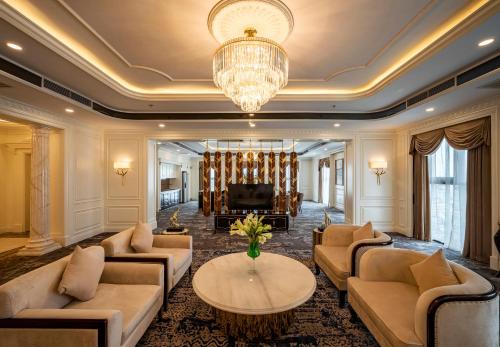 a living room with couches and a table and a piano at Muong Thanh Luxury Saigon Hotel in Ho Chi Minh City