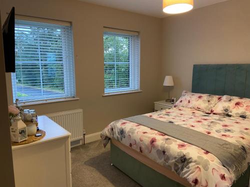 a bedroom with a bed and two windows at Beautiful private room and bathroom in Ballycastle