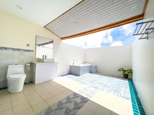 a bathroom with a toilet and a sink and a window at Rehendhi Villa in Maafushi