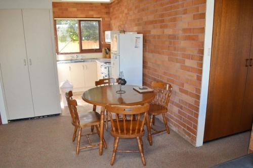 a kitchen with a table and chairs and a brick wall at Anglers Lodge 4 in South West Rocks