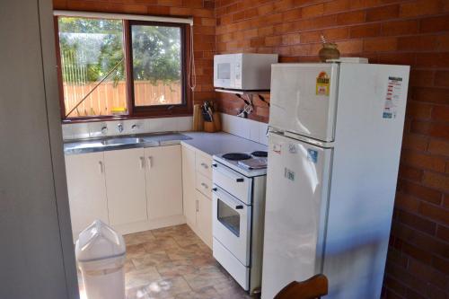 a kitchen with white appliances and a brick wall at Anglers Lodge 4 in South West Rocks