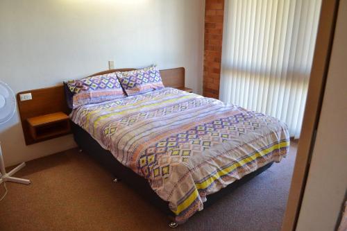 a bedroom with a bed with a quilt and pillows at Anglers Lodge 4 in South West Rocks