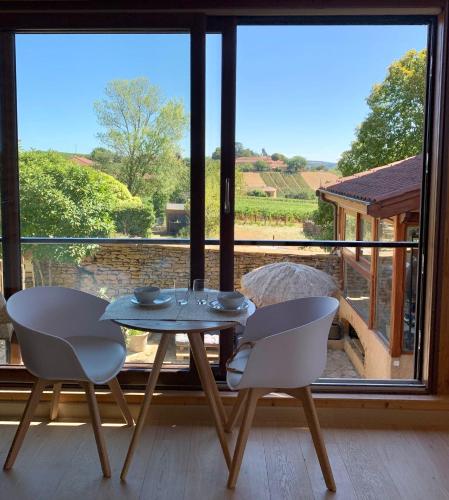 une table et des chaises dans une pièce avec une grande fenêtre dans l'établissement Songes de vigne, à Bagnols