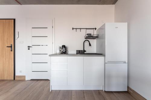a kitchen with white cabinets and a refrigerator at Apartamenty Przystanek Morska in Gdynia