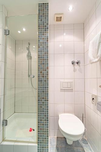a bathroom with a shower and a toilet and a tub at Parkhotel Sonnenberg in Eltville