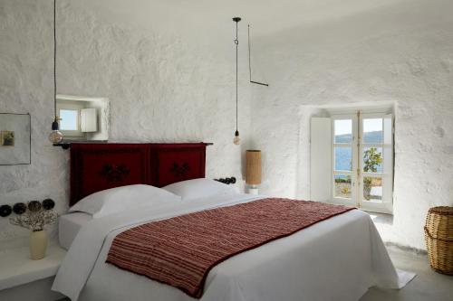 una camera bianca con un grande letto bianco e una finestra di Santa Irini Retreat a Thirasia
