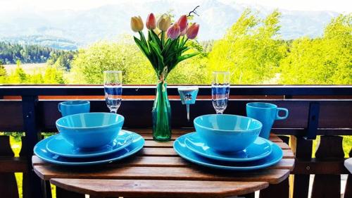 einem Holztisch mit einer Vase aus Tulpen in einer grünen Vase in der Unterkunft Ferienwohnungen MONFREDA Made for better days in Drobollach am Faakersee