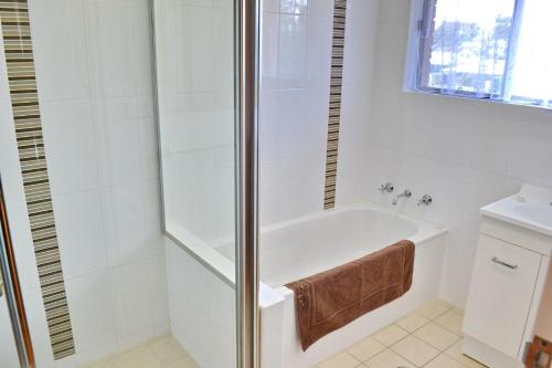 a white bathroom with a tub and a shower at Woody Wonder in South West Rocks