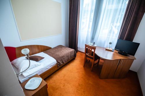 um quarto com uma cama e uma secretária com um computador em Emerald Boutique Hotel em Târgu-Mureş
