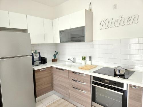 cocina con armarios blancos y nevera de acero inoxidable en Melony Apartments Yam Suf Street, en Eilat