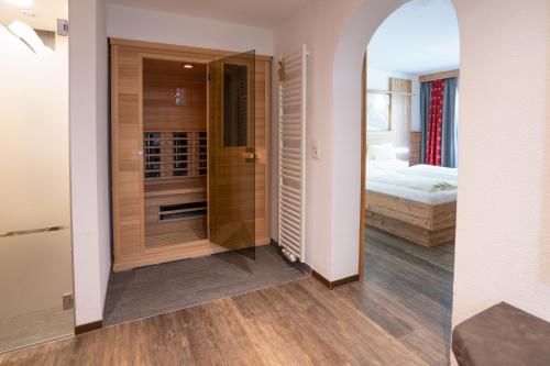 a room with a walk in shower and a bedroom at Hotel Gundolf in Sankt Leonhard im Pitztal