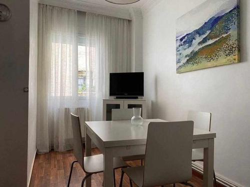 une salle à manger blanche avec une table et une télévision dans l'établissement Apartamento Las Murallas, à Pampelune