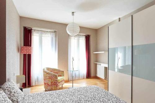 a bedroom with a bed and a chair and windows at Apartamento Ayla Ayuntamiento in Pamplona