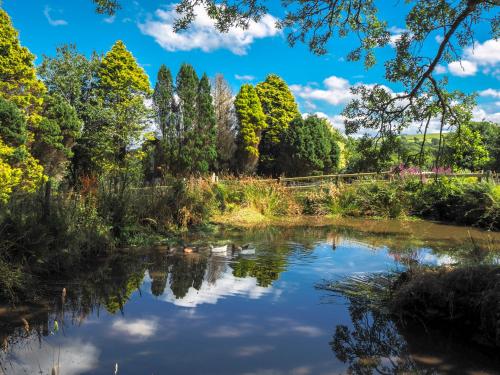 une rivière dans un parc avec des arbres et des nuages dans le ciel dans l'établissement Ty Cnocell, à Boncath