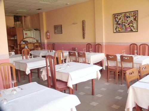 a dining room with white tables and wooden chairs at Hostal CC in Aranda de Duero