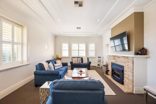 a living room with blue couches and a fireplace at 'Micah House' A Central Mudgee Art Deco Hideaway in Mudgee