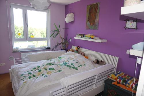 a bedroom with a white bed with a purple wall at Doppelzimmer mit ensuite Bathroom zur Wiesn in Munich