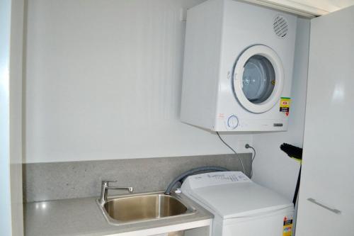 a small kitchen with a sink and a washing machine at Waterford Apartment 5 in South West Rocks