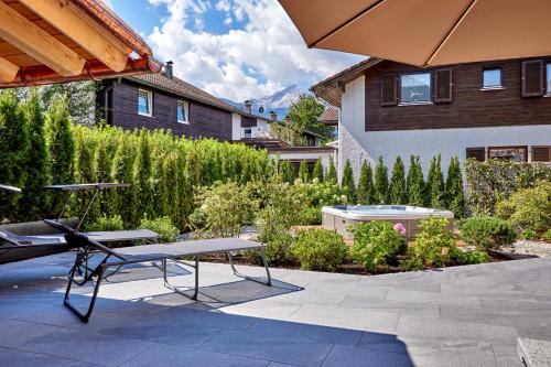 a patio with a table and a bench in a garden at Sunshine Apartment Spirit of Deer in Garmisch-Partenkirchen
